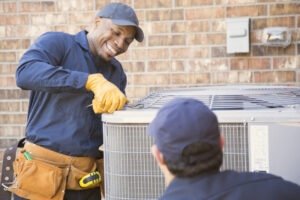 Two air conditioner technicians prepare to start spring air conditioning tune up with tools.