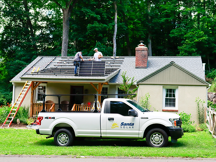 Santa Solar work truck parked in front of house with solar team installing panels