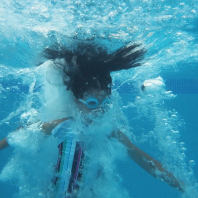 girl jumping into pool underwater