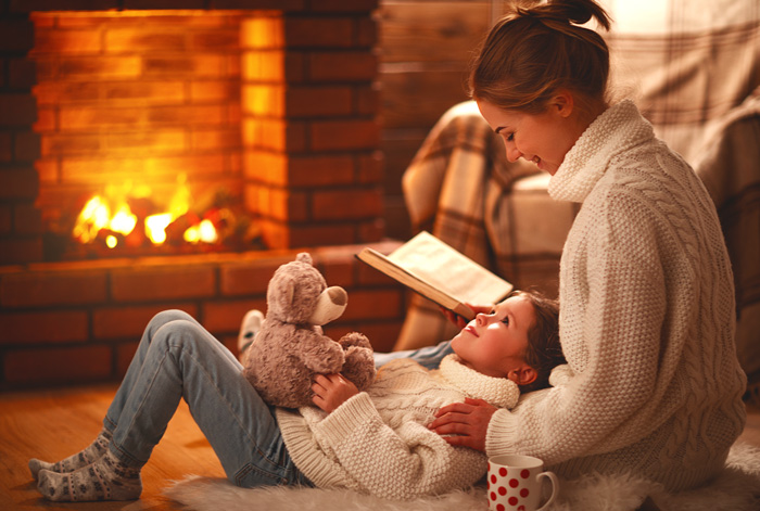 People read and snuggle by a propane gas fireplace logset